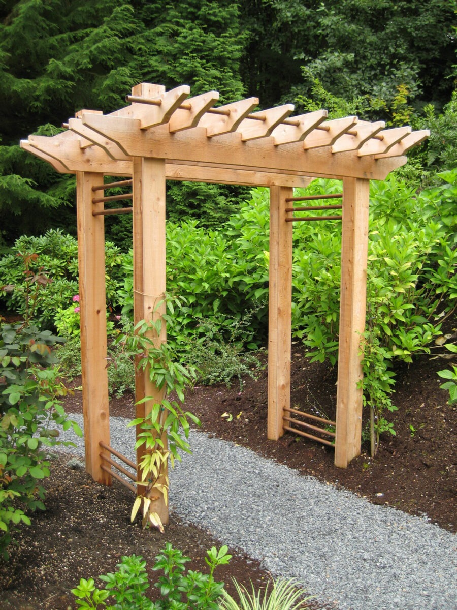 All wood arbor constructed over a rock walking path in a garden in Seattle, Washington.