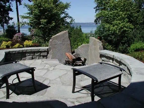 Round custom built patio with large rock fire pit over looks the Puget Sound in Seattle, Washington.