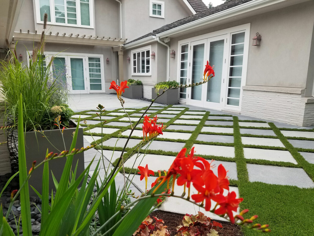 LIfestyle Landscapes laid grass pavers in a manicured backyard with bright red crocosmia diablitos in bloom near Seattle, Washington.